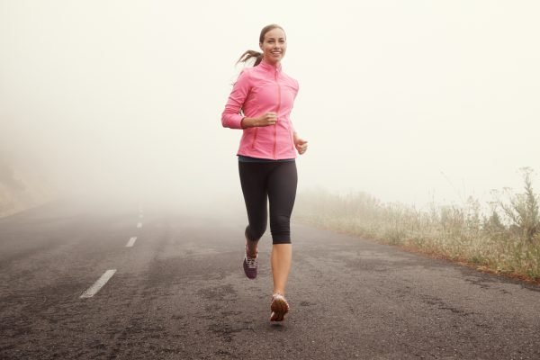 Shot of a young woman jogging on a country road on a misty morning